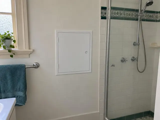 Neat white access panel on a bathroom wall beside a shower and towel rail in Hamilton South